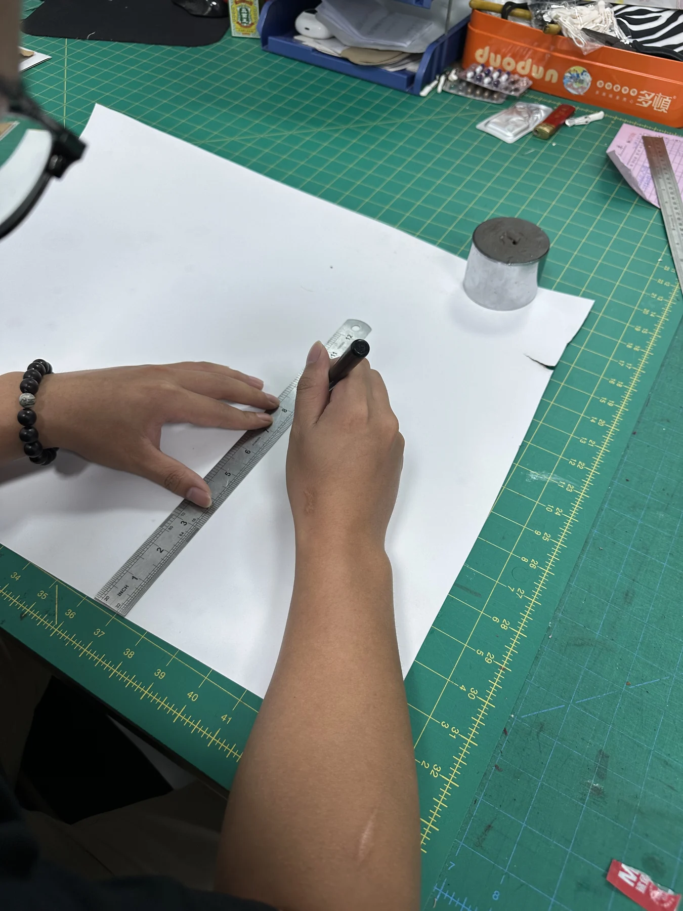 Custom bag paper pattern measurement and preparation Hongzhao bag pattern maker checking measurements on a paper pattern over a gridded cutting mat